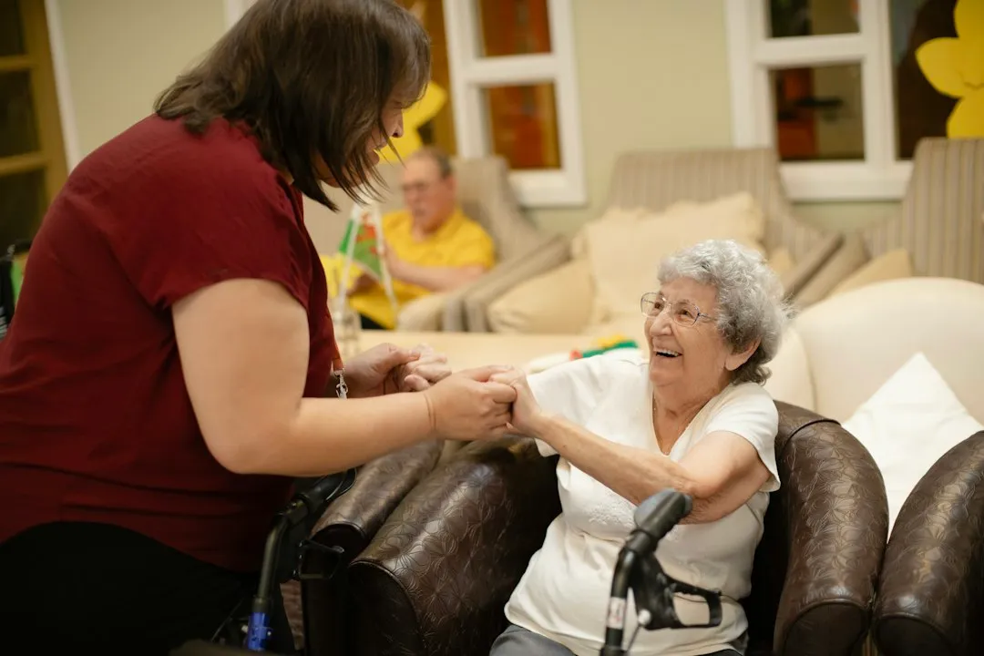 A carer and an older woman with a walking frame, laughing together