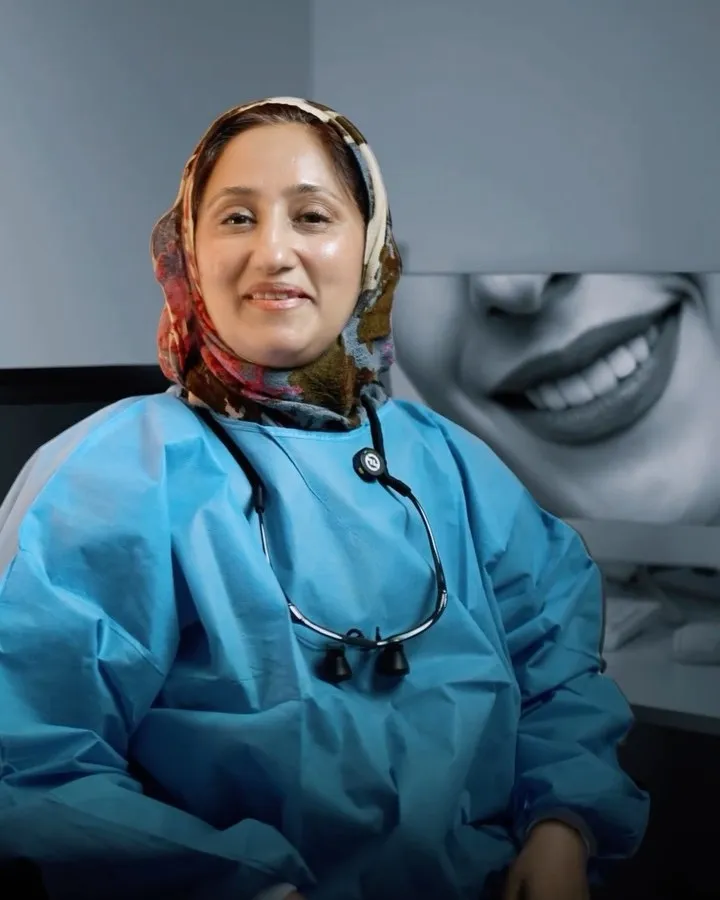 Dr. Rifat in blue scrubs with a stethoscope, smiling